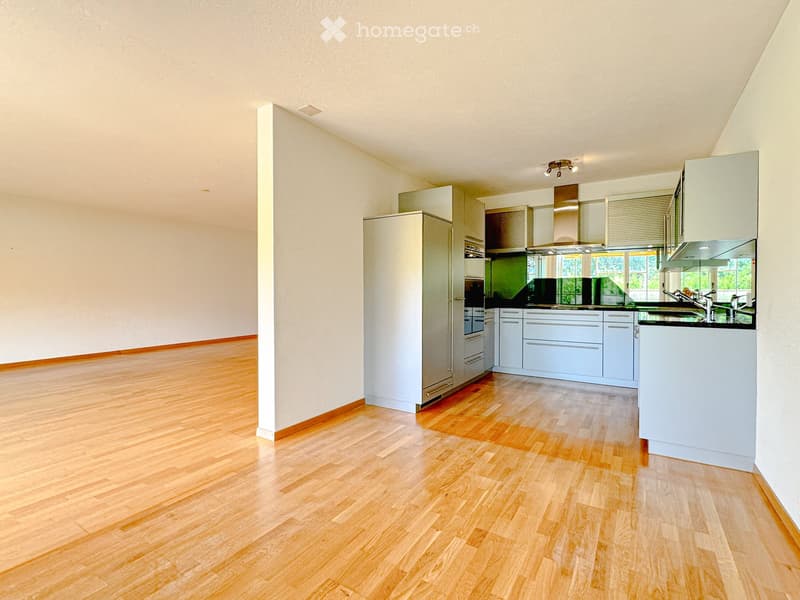 Modern kitchen with light-colored cabinets, stainless steel appliances, and wooden flooring.