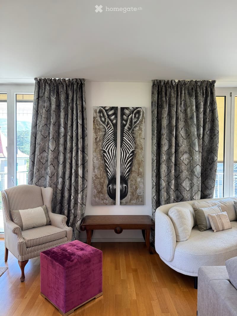 Living room with light-colored sofa, striped armchair, wooden coffee table, purple ottoman, and large zebra artwork on the wall.