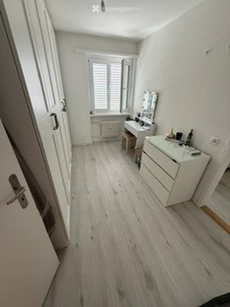 Bright, modern bathroom with white walls, wooden flooring, a vanity with a mirror, and a sink.