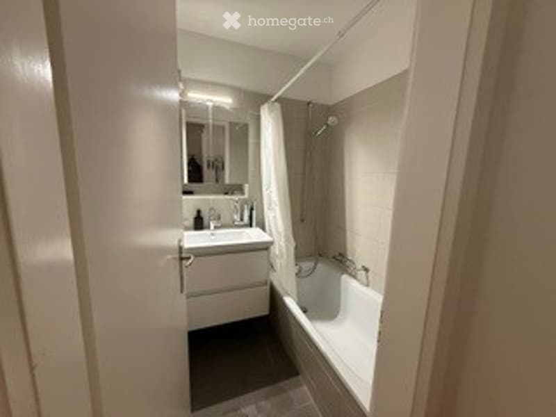 Modern bathroom with a white sink, mirror, and bathtub. The space features clean lines and a neutral color palette.