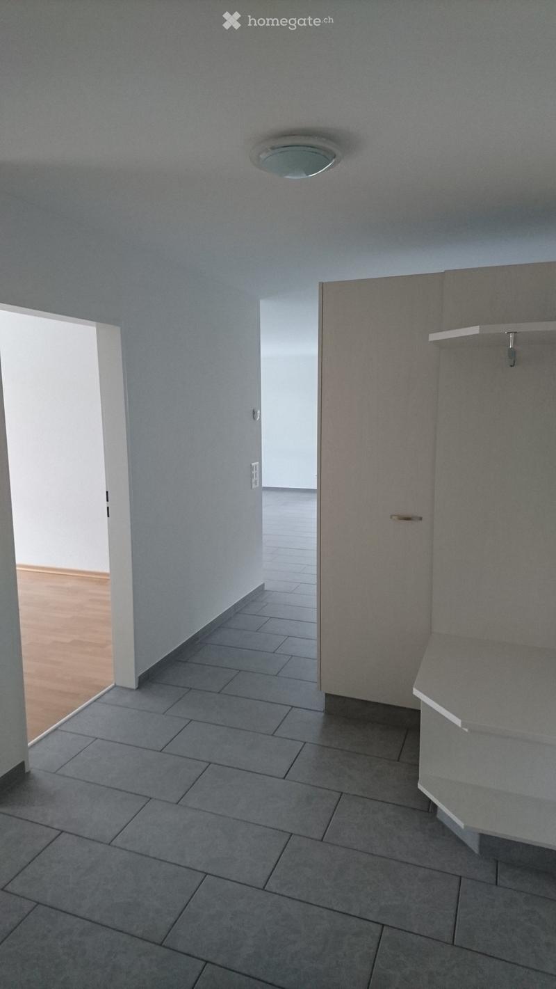 Empty room with tiled floor and grey walls, featuring a built-in closet with shelves and a recessed ceiling light.