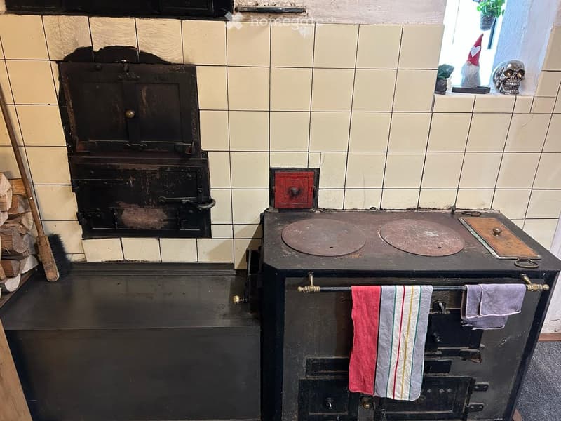 Vintage kitchen with a large black stove and oven, tiled walls, and a towel rack with towels.