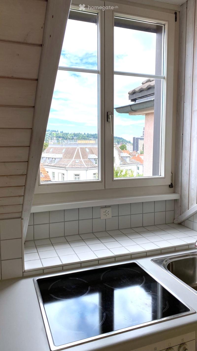 Modern kitchen with an induction stove, sink, and large windows offering a view of the cityscape.