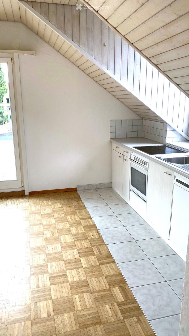 Modern kitchen with white cabinets, wooden herringbone flooring, and built-in appliances including an oven, sink, and dishwasher.