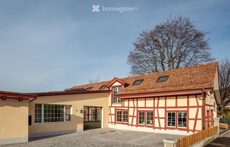 2-storey house with brick walls, brown roof, red trims, large windows, and a driveway