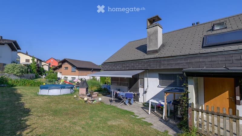 Backyard with a swimming pool, patio area, outdoor furniture, and a clothesline. The house has a modern design with a covered patio and a chimney.