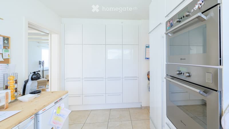 Modern kitchen with white cabinets, stainless steel oven, dishwasher, and coffee maker on the counter.