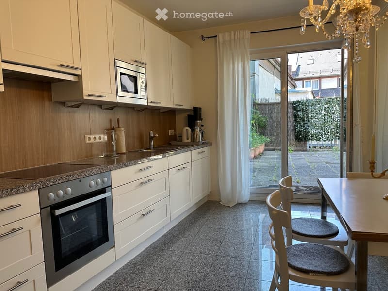 Modern kitchen with white cabinets, granite countertops, stainless steel appliances, and a dining area with a table and chairs.
