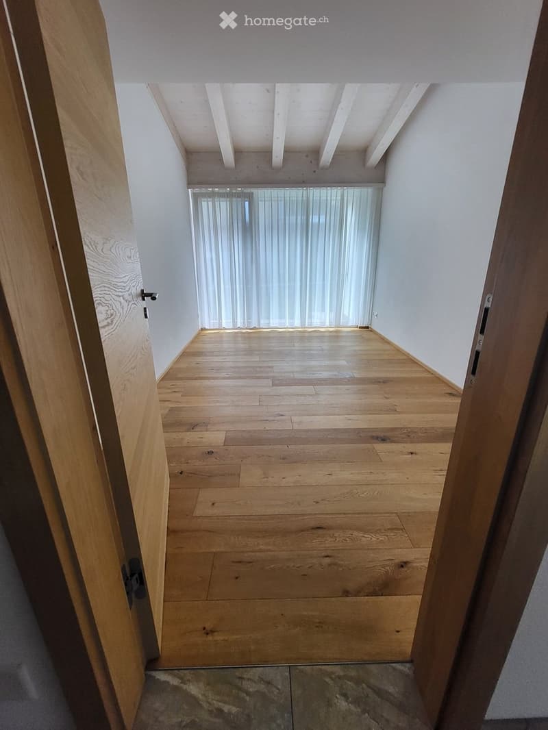 Empty room with wooden flooring, white walls, and a skylight above. No furniture or equipment present.