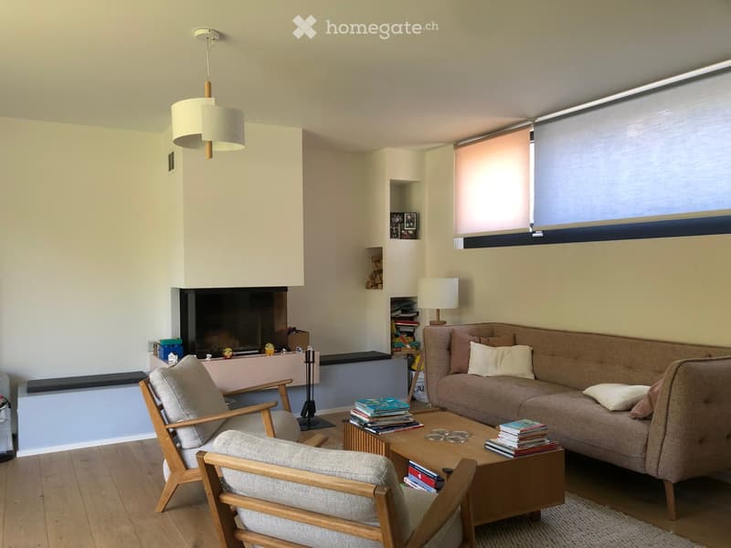 Modern living room with a fireplace, a sofa, a coffee table, a wooden chair, and a table lamp.