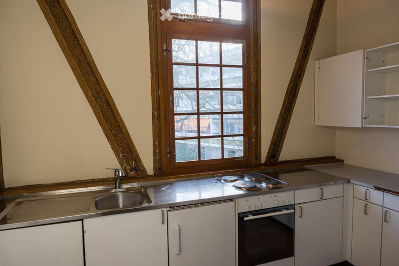 Gas stove, electric oven, stainless steel sink, white cabinets, large window, wooden beams, small countertop