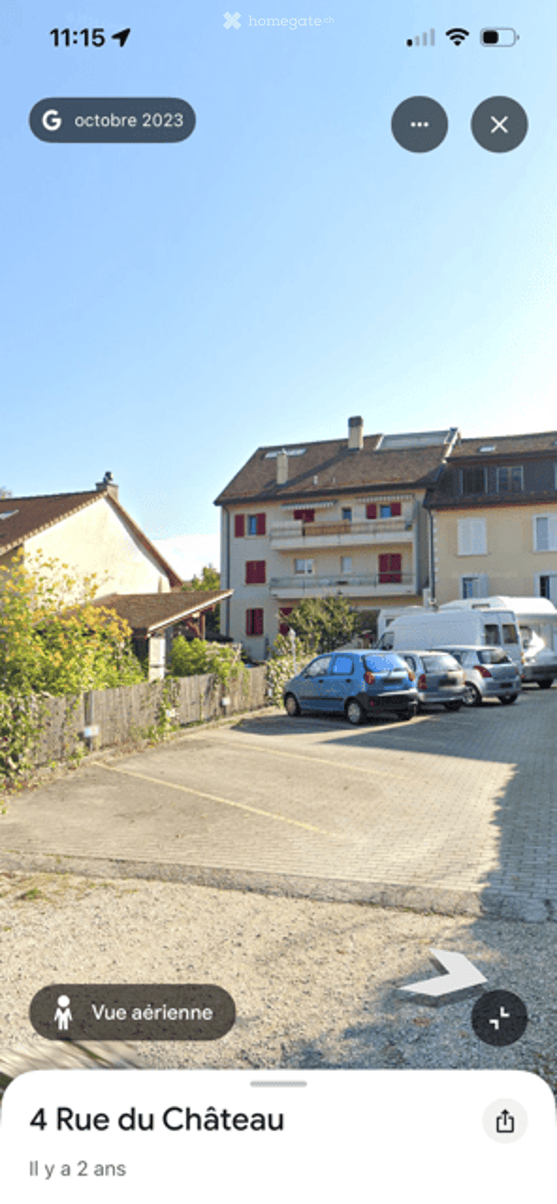 A multi-story residential building with multiple apartments, surrounded by a parking area with several parked cars.