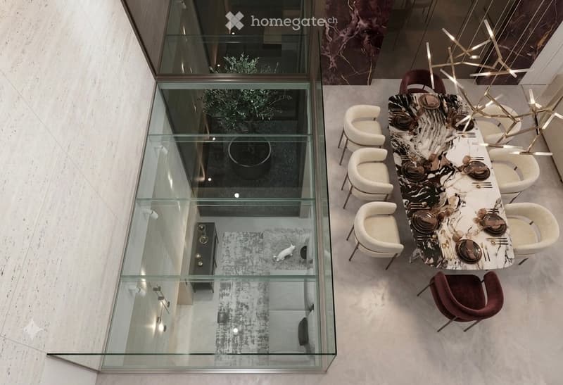 A modern dining area with a long, black and white marble dining table set with plates, cutlery, and glassware, surrounded by white and brown chairs. A sleek, contemporary chandelier hangs above. A glass floor-to-ceiling window offers a view into a living