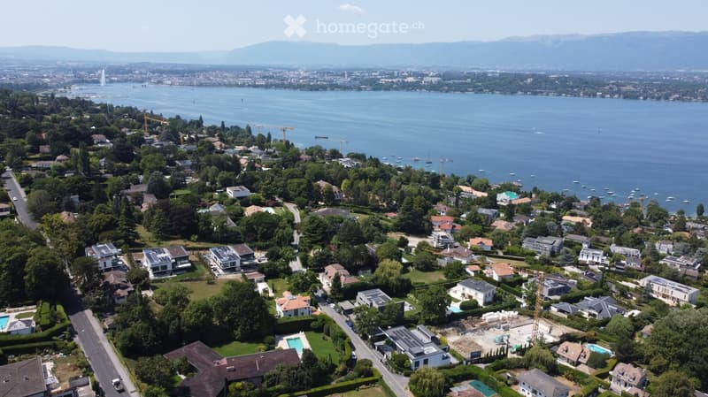 Aerial view of a suburban neighborhood with numerous houses, green spaces, and a large body of water in the background.