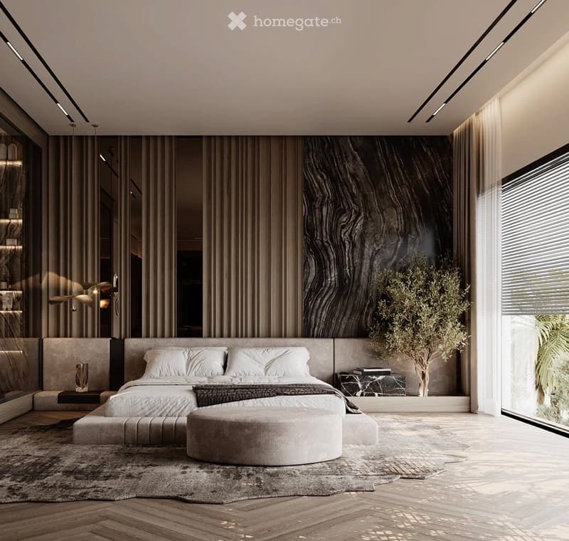 Modern bedroom with a large bed, ottoman, bench, side table, and decorative plant. Features sleek curtains, a marble accent wall, and recessed lighting.