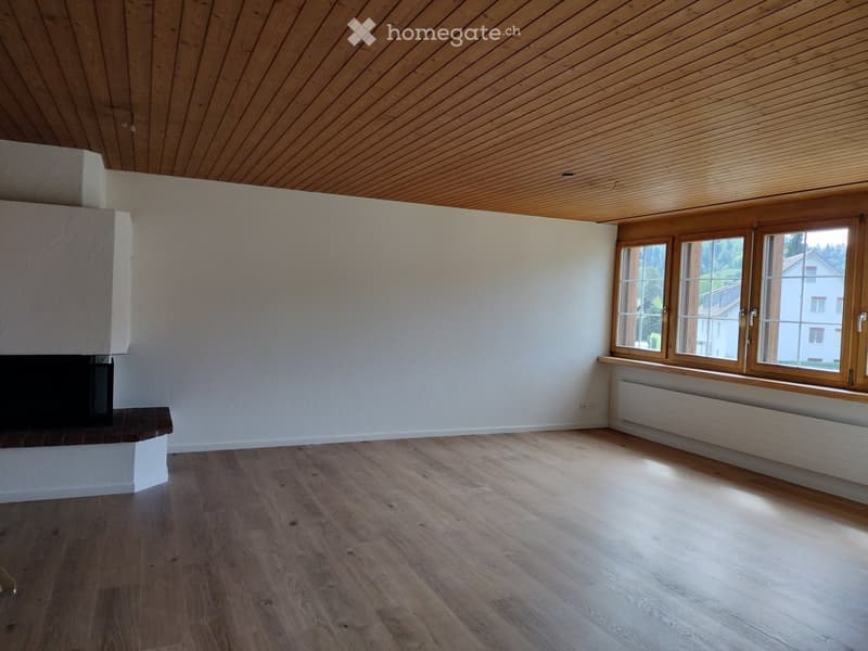 Unfurnished Room. Empty room with wooden flooring, white walls, and a fireplace. Large windows with wooden frames allow natural light to enter.