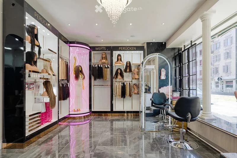 Modern salon interior with sleek black and white decor, large mirrors, mannequins displaying hair pieces, and stylish chairs.