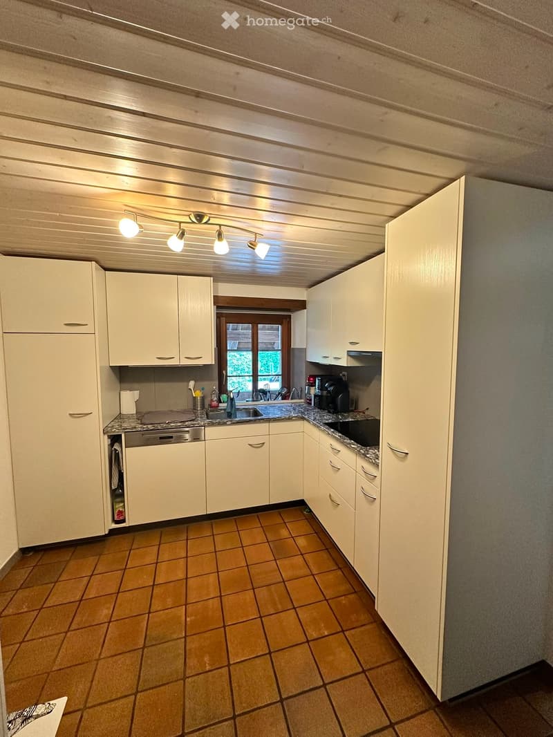Bright kitchen with white cabinets, granite countertops, and a tiled floor. Features a sink, dishwasher, and coffee maker.