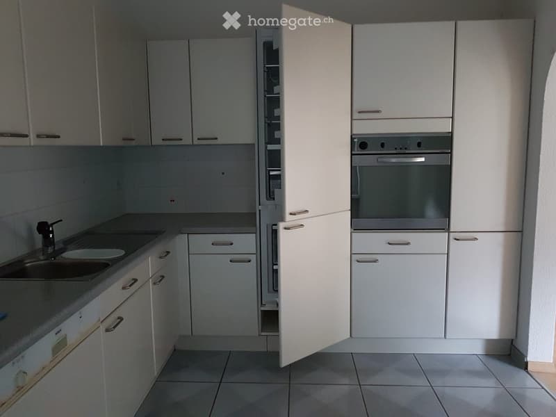 Modern kitchen with white cabinets, stainless steel appliances, and tiled flooring.