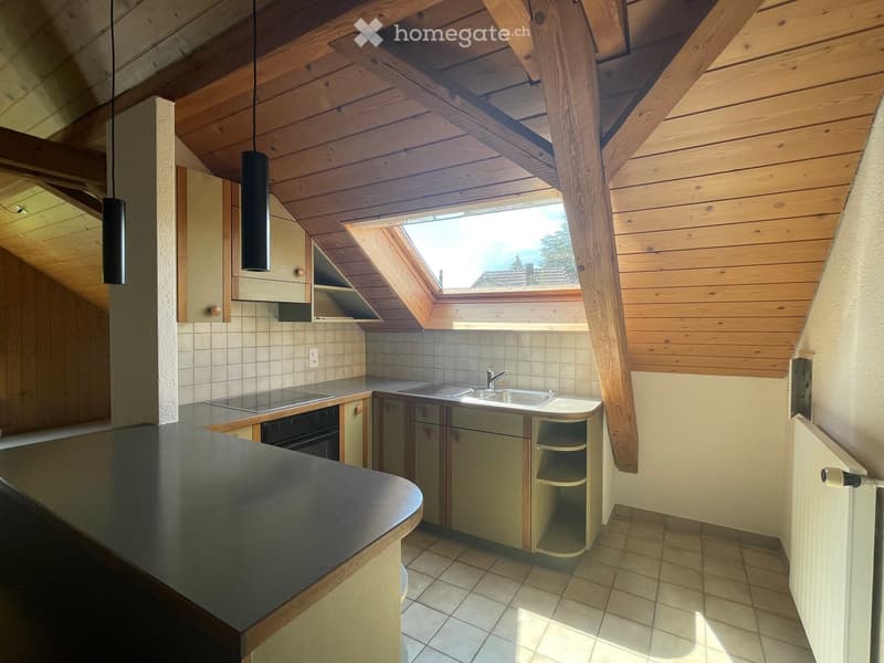 Modern kitchen with wooden beams, skylight window, stainless steel sink, oven, and cabinets.