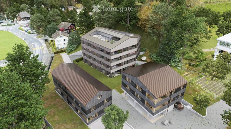 Aerial view of a modern residential complex with multiple buildings, surrounded by greenery and a road.