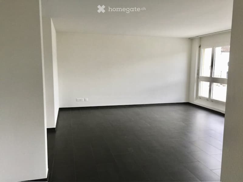 Completely empty room with bare white walls and dark wooden flooring. No furniture or equipment.