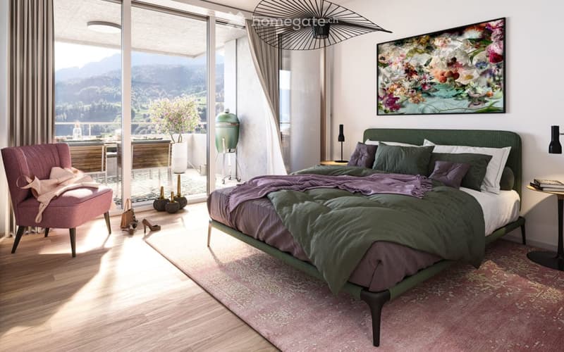 Modern bedroom with a large bed, nightstand, pink armchair, artwork, and a scenic mountain view through large windows.