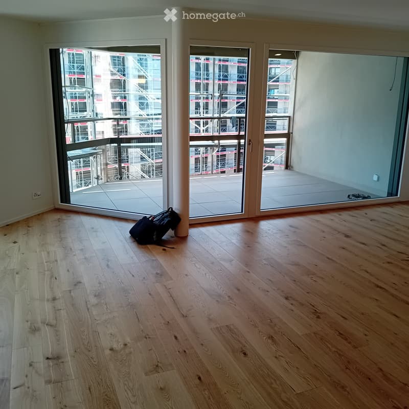 Empty room with wooden flooring and large sliding glass doors leading to a balcony.