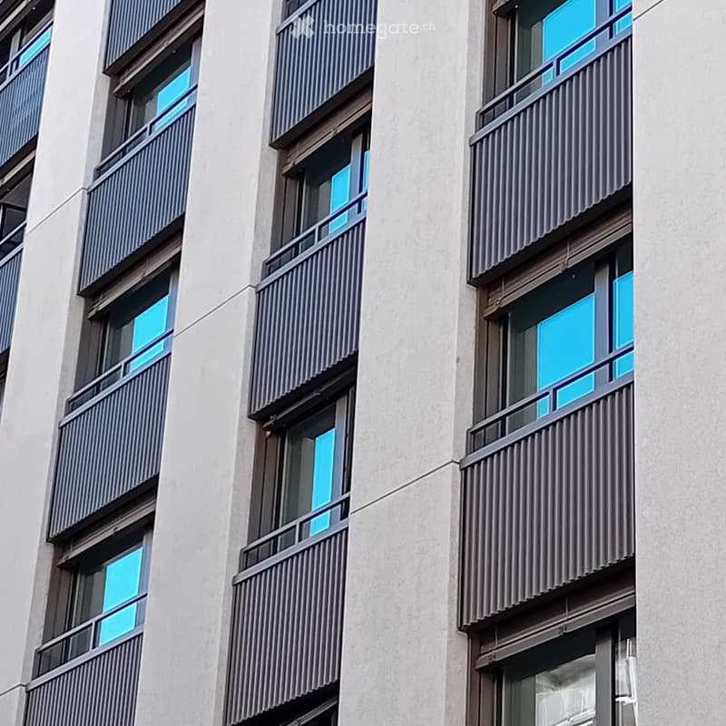 Modern building with multiple floors, each floor has a balcony, white walls, and gray railings