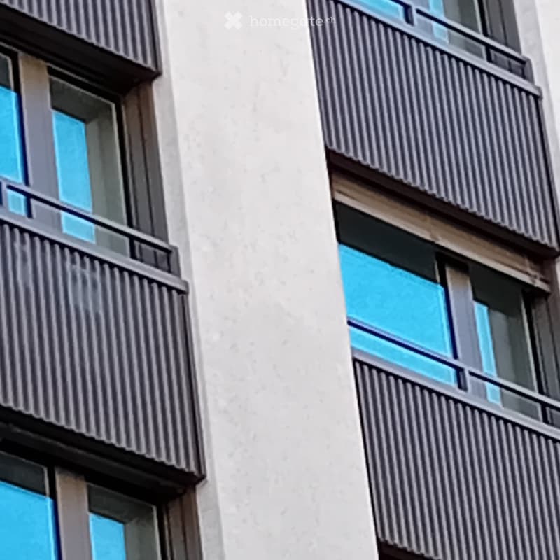 Modern building with glass windows, balconies, white walls, gray railings