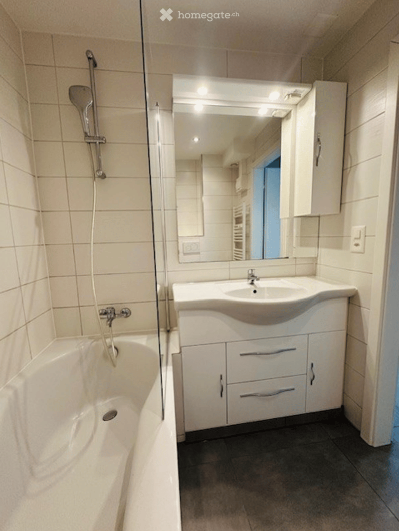 Modern bathroom with a white bathtub, a sink with a modern cabinet, and a large mirror with built-in lighting.