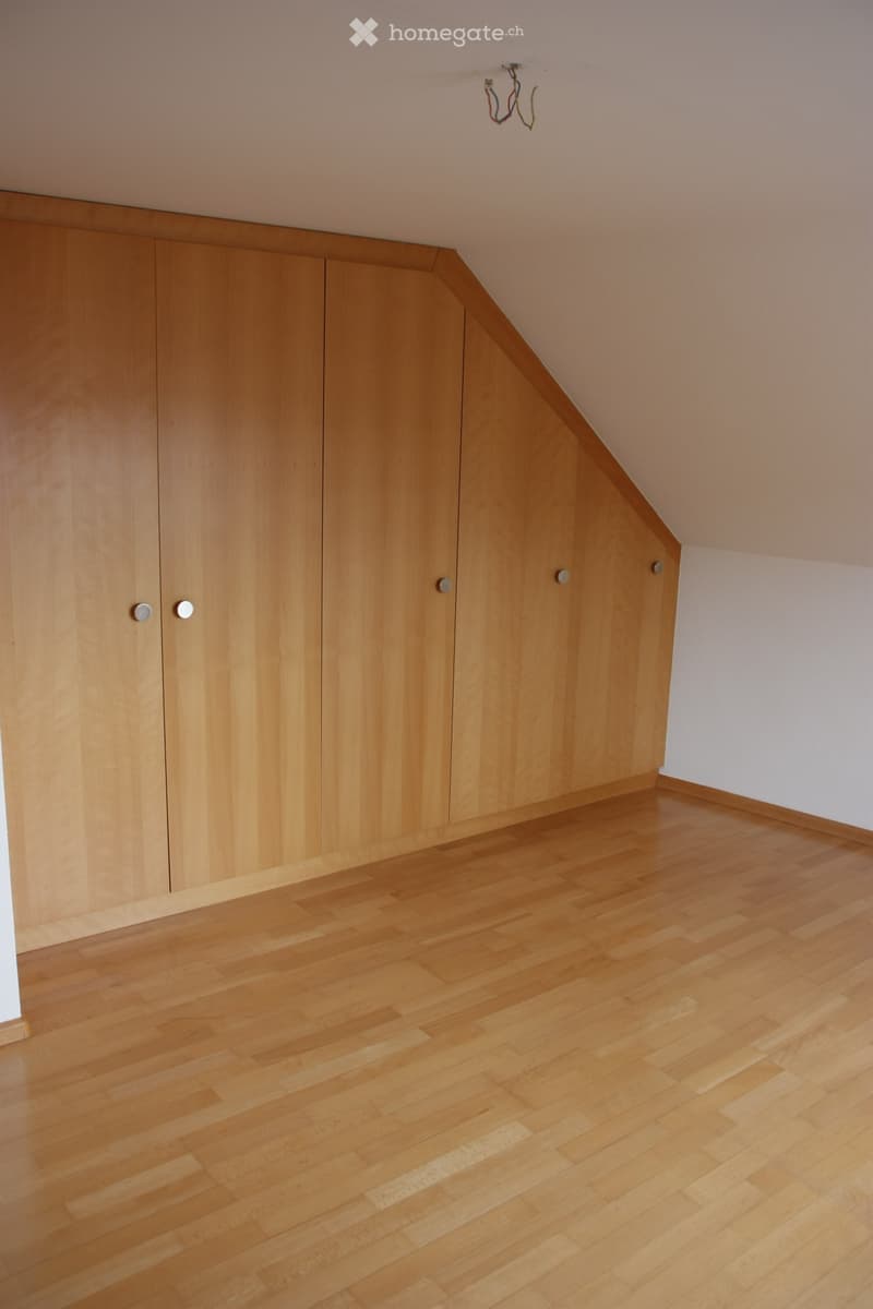 Wooden staircase with a sleek, modern design, featuring light-colored wood steps and handrails, and a smooth, light-colored wall on one side.