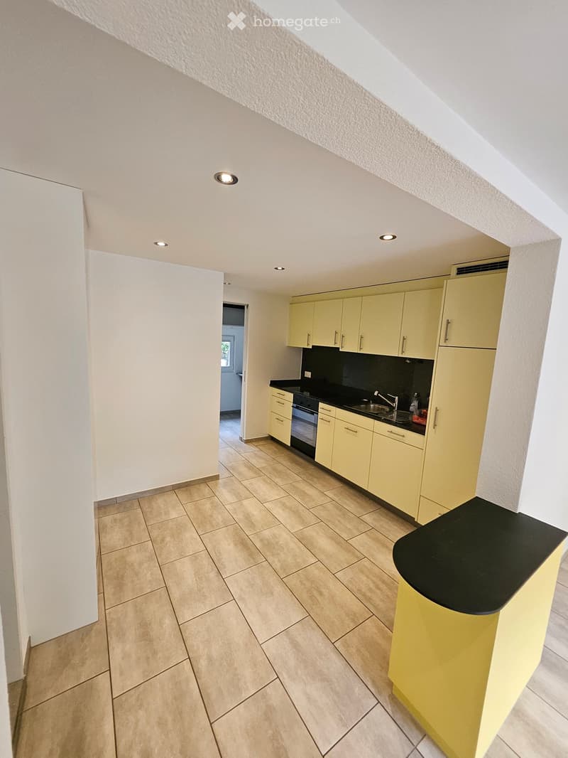 an empty kitchen with yellow cabinets, tiled flooring, and a modern center island