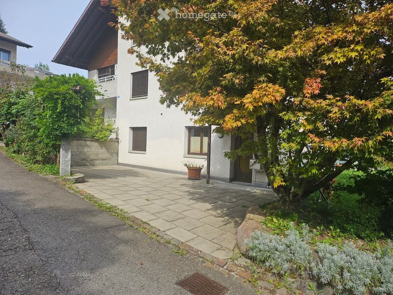 two-story white house, tile walkway, tree, potted plant, shrubs, gravel pathway