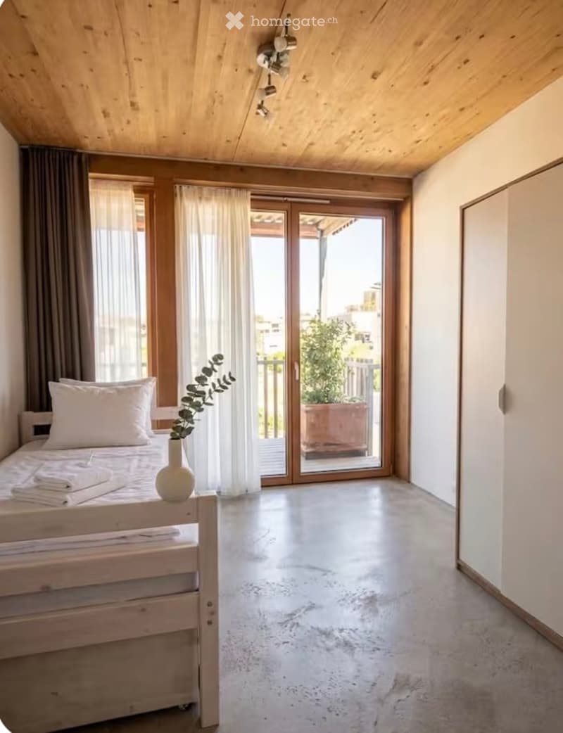 Modern bedroom with a wooden bed, white wardrobe, large windows with curtains, and a sliding glass door leading to a balcony.