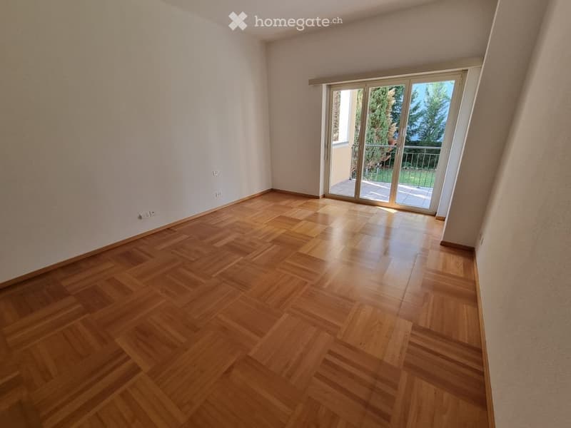 Empty room with wooden flooring and large sliding glass doors leading to a balcony.
