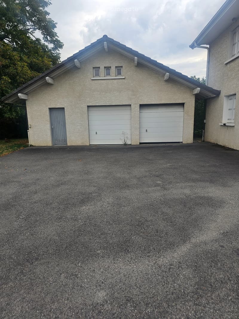 Two-car garage with a small side door, light-colored exterior, and a paved driveway.