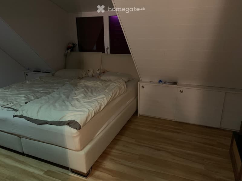Cozy attic bedroom with a single bed, nightstands, and toys on the bed.