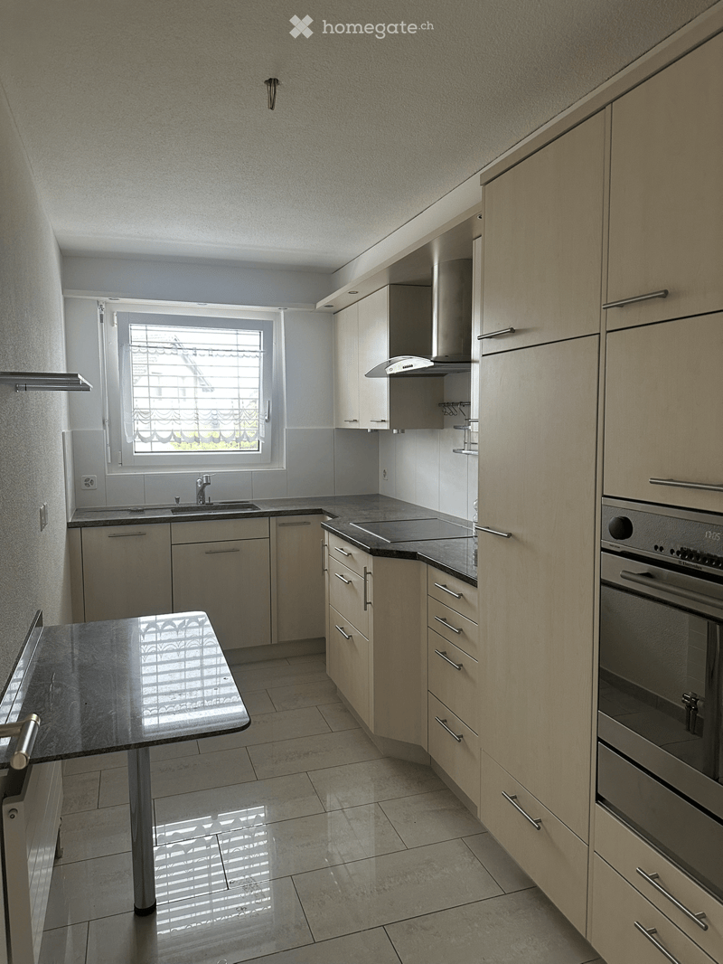 Modern kitchen with light wood cabinets, stainless steel appliances, and a central island.