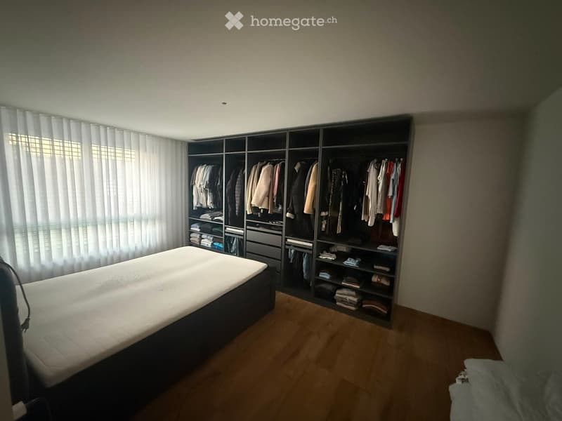 Modern bedroom with a large bed, built-in wardrobe, and wooden flooring.