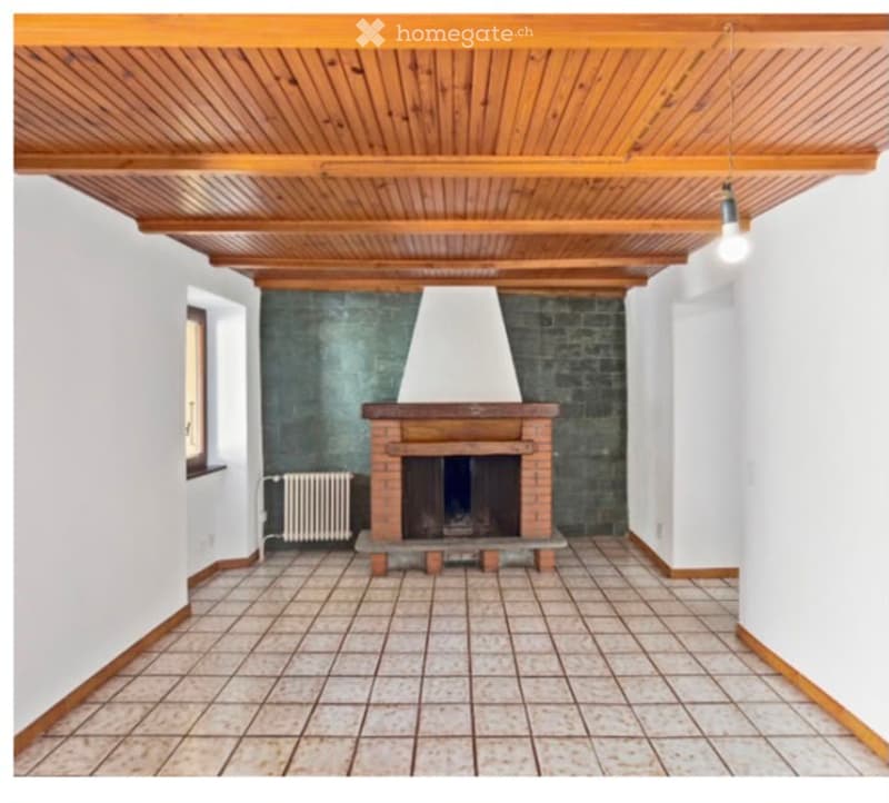 Empty room with wooden ceiling, tiled floor, white walls, and a brick fireplace with a white chimney hood.