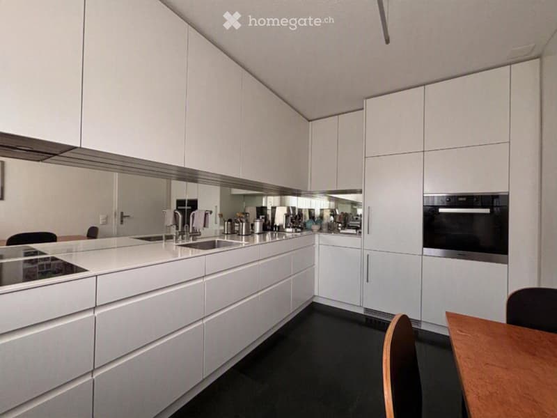 Modern kitchen with white cabinets, stainless steel appliances, and a sleek countertop.