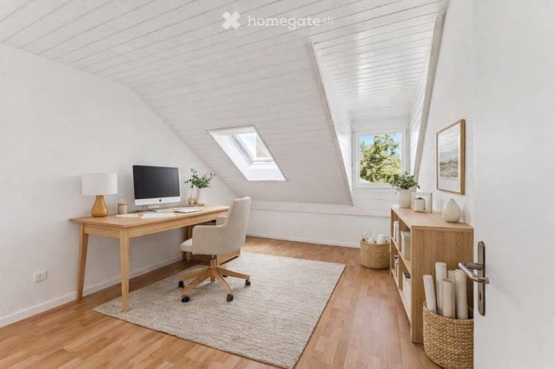 Bright, airy attic office with wooden floors, white paneled walls, large windows, skylights, and a cozy workspace setup.