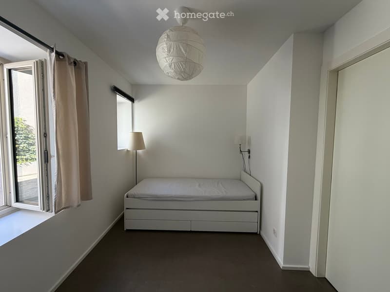 Bedroom. Minimalist bedroom with a white bed, a hanging paper lantern light fixture, a wall-mounted lamp, and a curtained window.