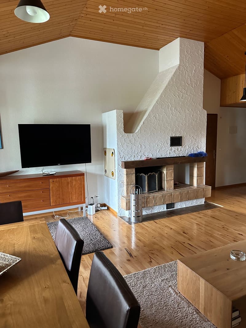 Living room with wooden floors, fireplace, sofa, table, chairs, and television.