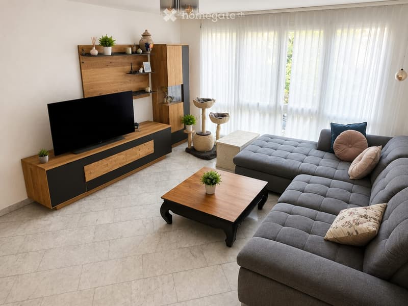 Modern living room with a grey sectional sofa, wooden coffee table, TV stand, cat tree, shelves, and potted plants.