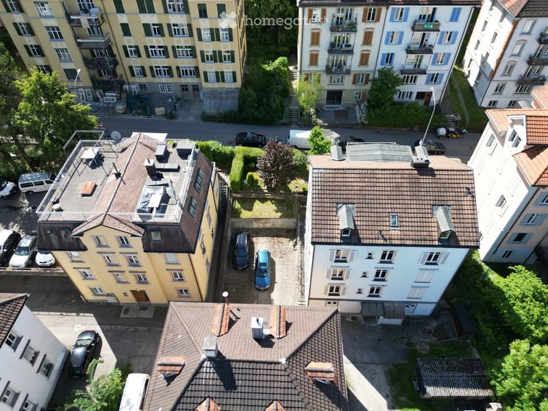 Aerial view of a multi-story residential building complex with multiple units, balconies, and surrounding greenery.
