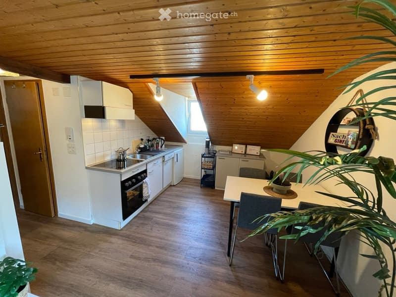 Modern kitchen with white cabinets, wooden ceiling, and a dining area. Features a stove, oven, sink, fridge, and a small table with chairs.