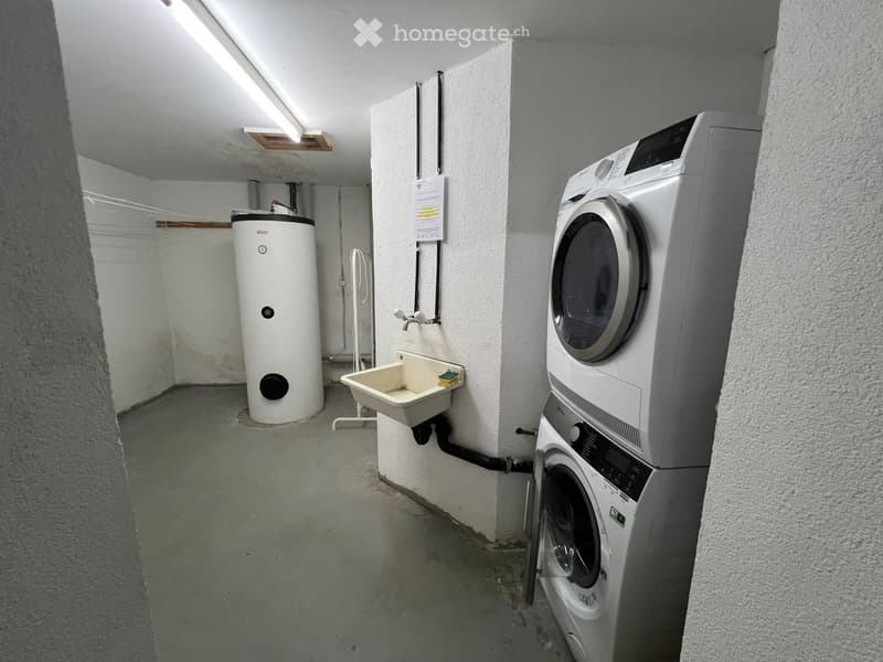 Utility room with a washing machine, dryer, water heater, and a small sink.