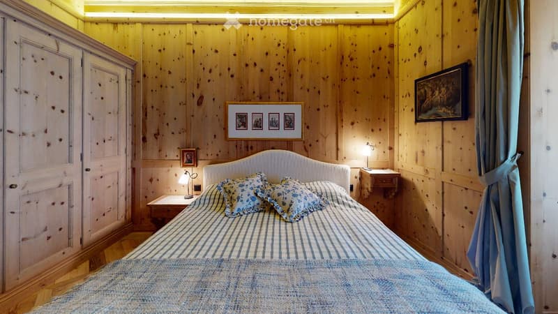 bedroom with wooden walls, bed, nightstands, lamps, cabinet, pillows, bedspread, curtains